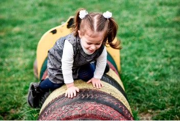 Niña jugando sobre neumáticos coloridos