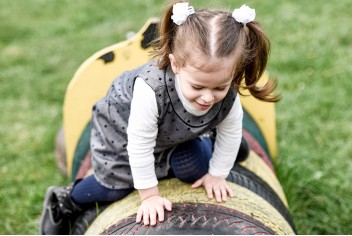 Niña jugando sobre neumáticos coloridos